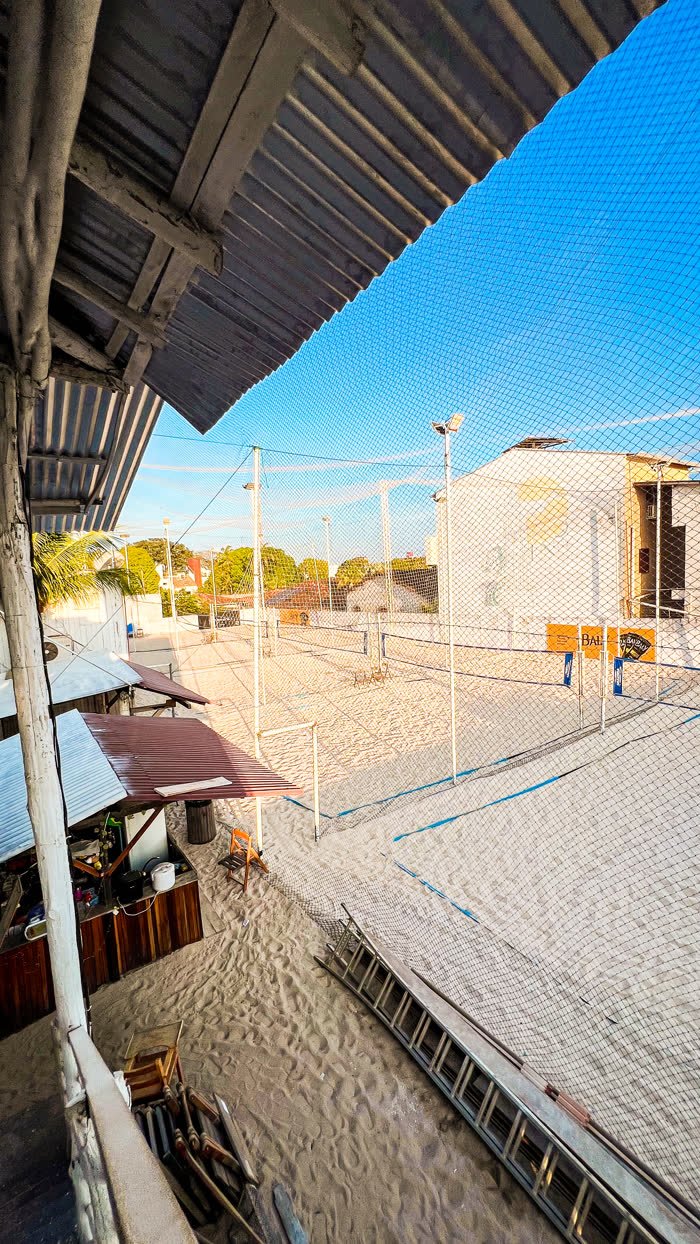 Vista do alto das quadras de areia do Rio Sand Club, com redes de vôlei montadas e céu azul