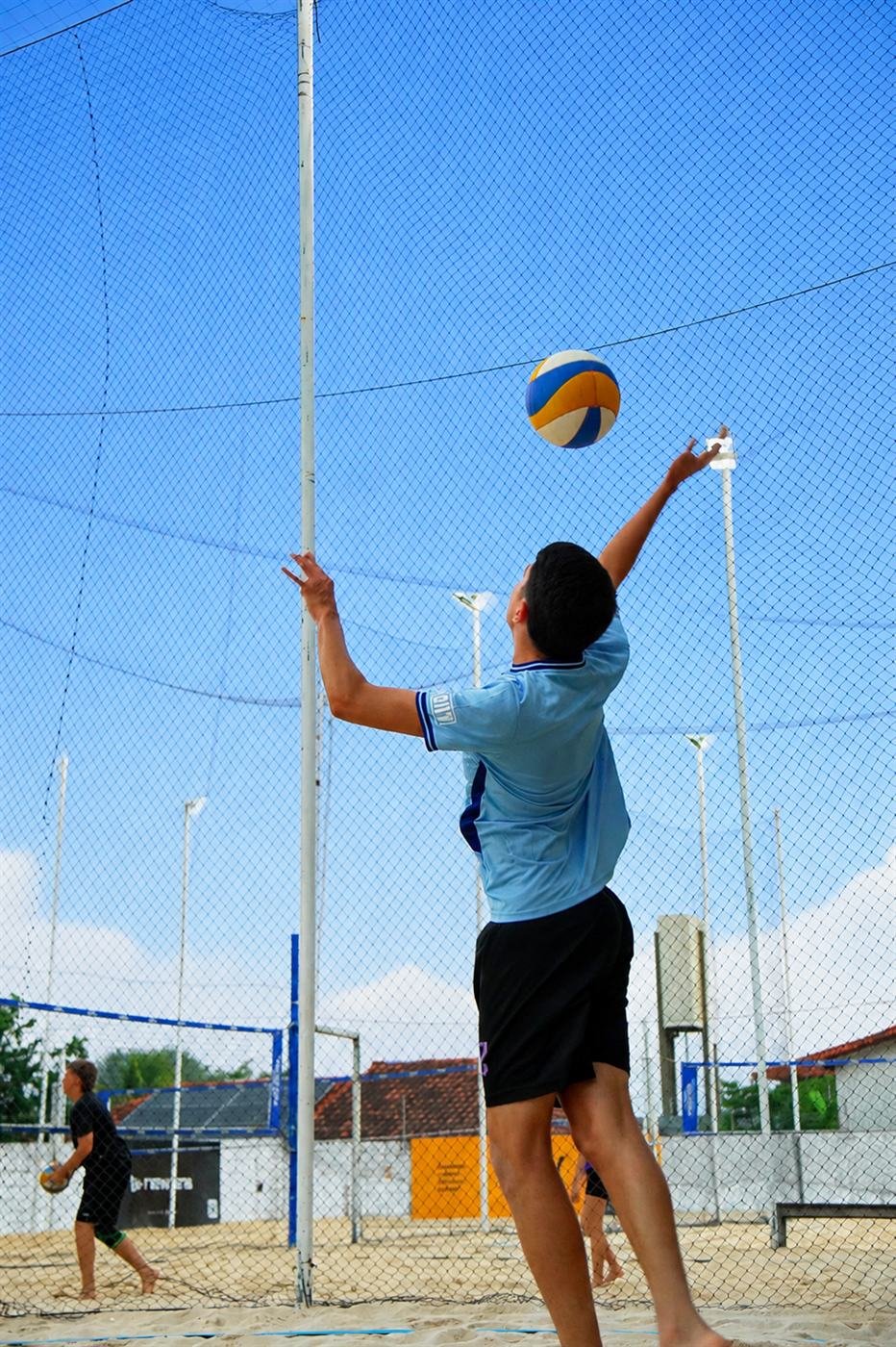 Jogador saltando para o saque durante partida de vôlei de areia no Rio Sand Club
